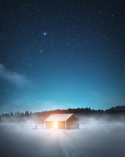 星夜下，雪地上的棕色木屋